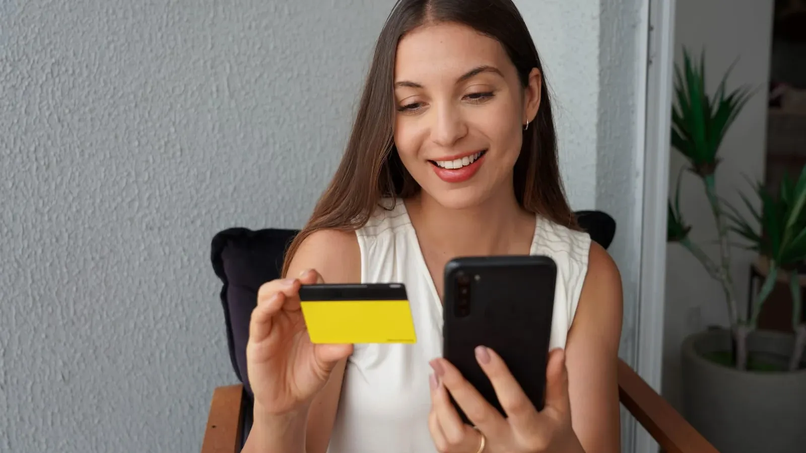 Hispanic girl reading and inserts credit card number on phone
